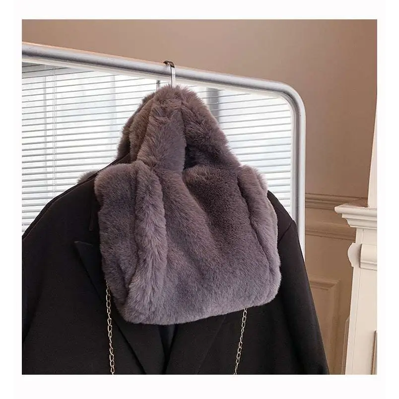 A gray faux fur chain plush handbag with soft plush texture hanging on a coat rack for stylish use