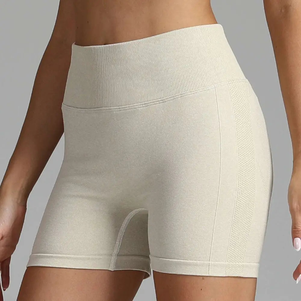 Cream-colored high waist seamless yoga shorts with ribbed waistband and mesh side panel for women