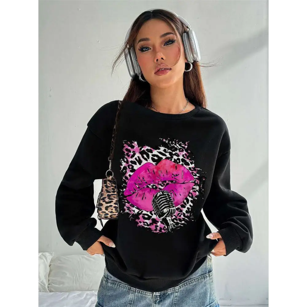 Black oversized crew neck sweatshirt featuring vibrant pink lips and leopard pattern graphic for casual wear