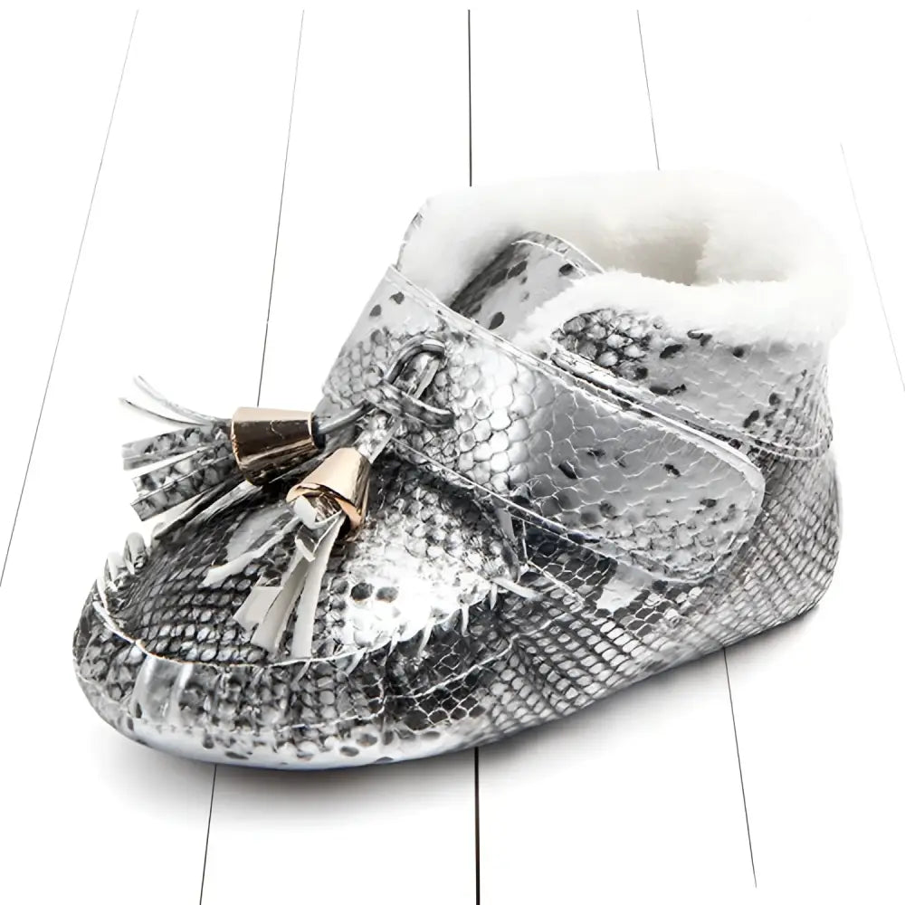 Silver snake-print baby shoes with white faux fur lining and gold-toned tassel accents for toddlers