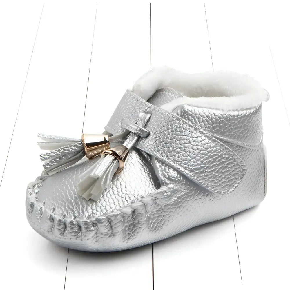 Silver textured leather baby shoes with white faux fur lining and pink metallic tassel accent for toddlers