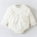 A delicate white newborn clothes jumpsuit with ruffled collar ribbed texture and lace trim on cuffs
