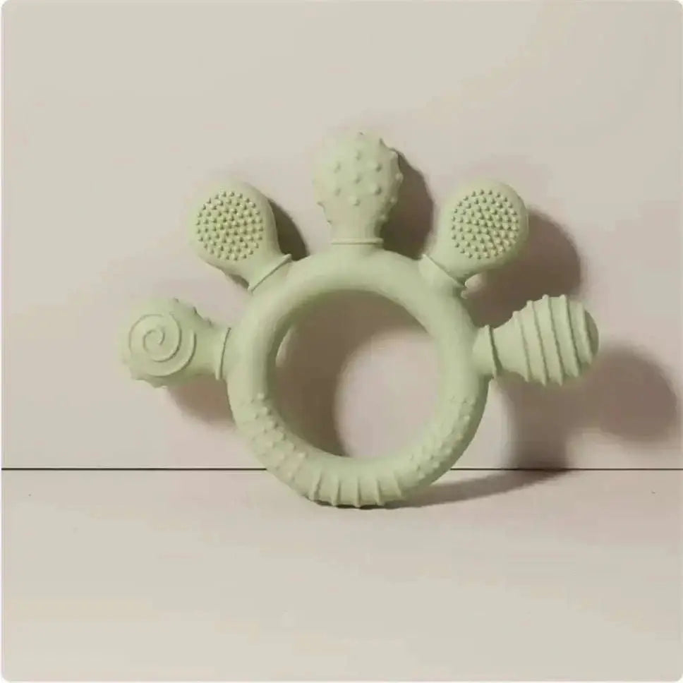 Pink silicone baby hand teether featuring a pale green silicone baby hand ring with five textured protrusions