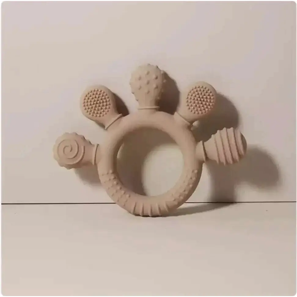 Beige silicone baby hand teether with textured bristles spiral pattern and ridged surfaces for soothing gums