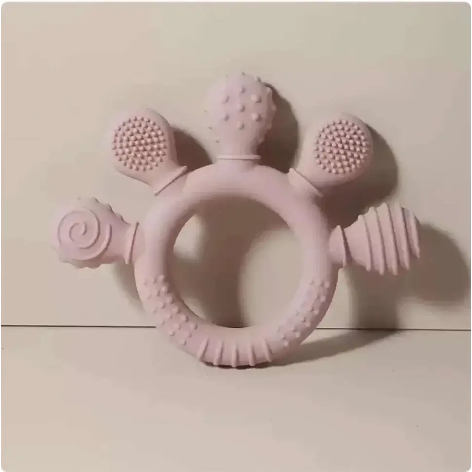 Pink silicone baby hand teether with textured rounded protrusions including bristles and ridges for soothing gums