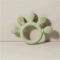Pink silicone baby hand teether featuring a pale green silicone baby hand design with five textured protrusions