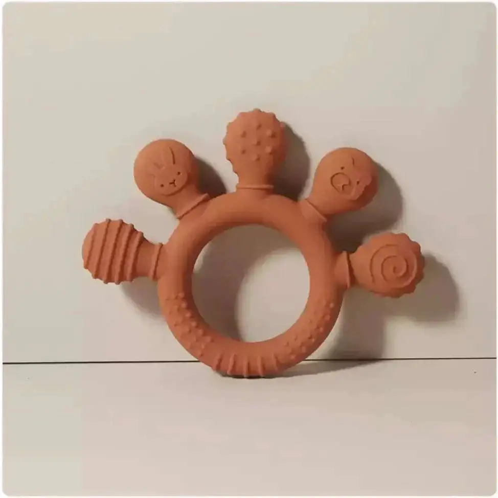 Pink silicone baby hand teether in terracotta color with four whimsical animal-shaped silicone baby hand protrusions