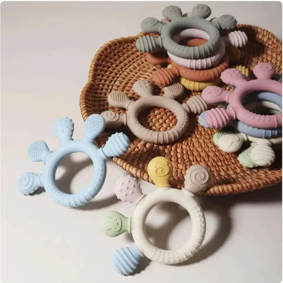Pastel pink silicone baby hand teether with soft textured surfaces and playful animal designs for infant use