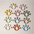 Pastel-colored silicone baby hand teethers in pink silicone baby with textured paw print design for soothing gums