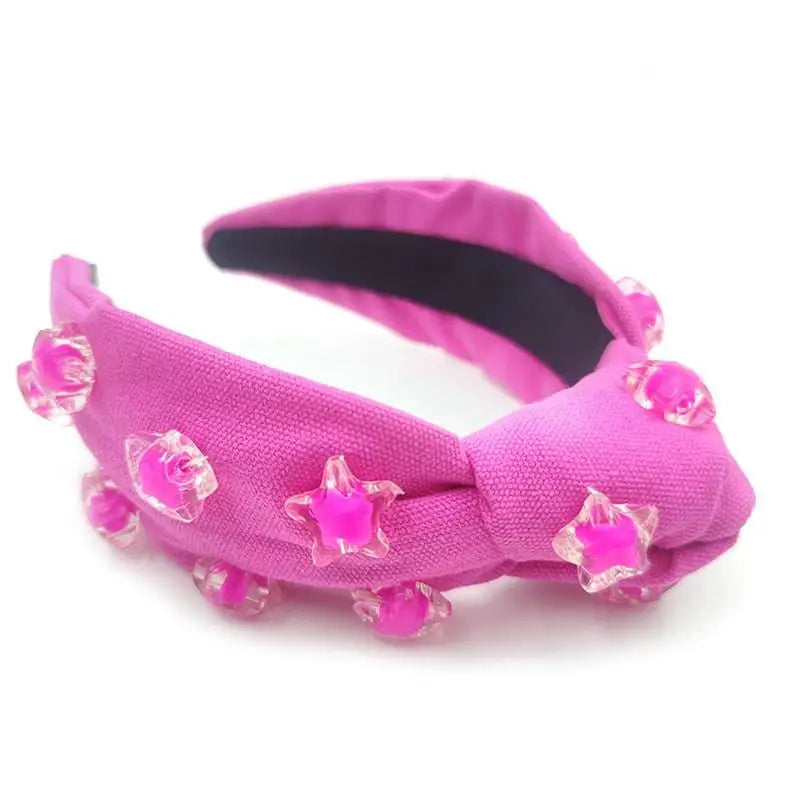A vibrant pink star solid holiday party headband with knotted design and clear star and rose embellishments