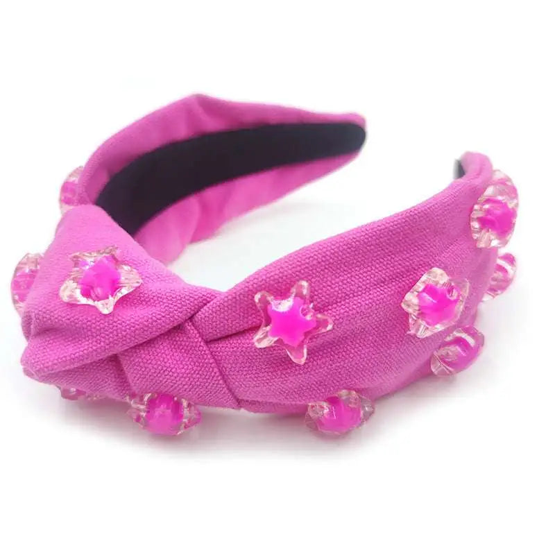 A vibrant pink star solid holiday party headband with knotted design and clear star shaped and round embellishments