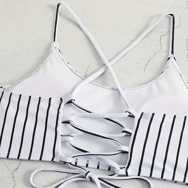 White and black striped bikini top with crisscross straps and lace-up back detail for a striped bikini split design