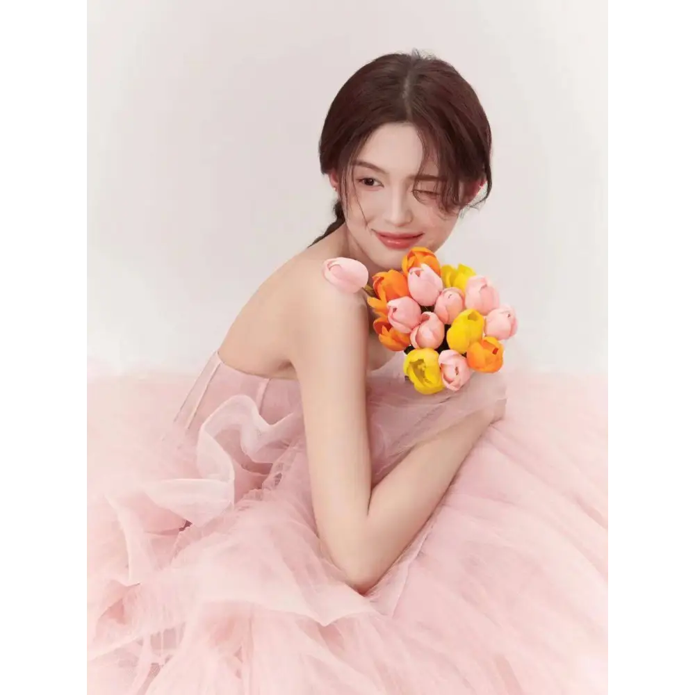 A soft pink tiered tulle dress with a flowing layered skirt and off-the-shoulder fairy temperament main design