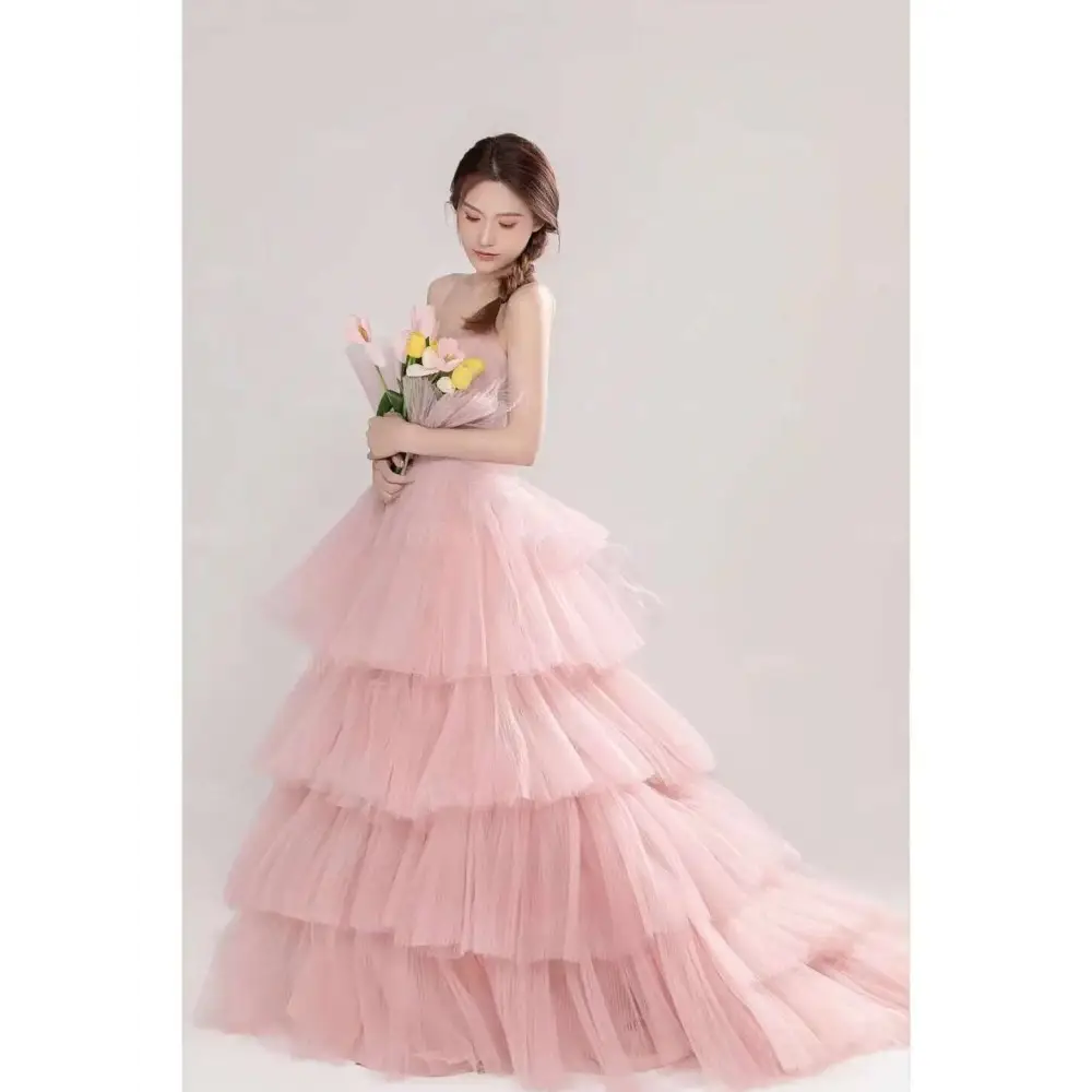 A soft pink tulle wedding photography dress with a strapless bodice and voluminous multi-tiered ruffled layers
