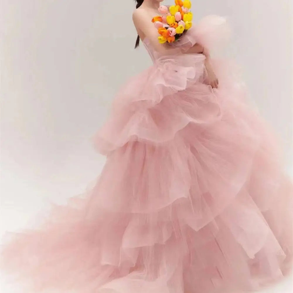 A soft pink tulle wedding photography dress with a strapless bodice and voluminous multi-tiered ruffled layers