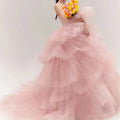 A soft pink tulle wedding photography dress with a strapless bodice and voluminous multi-tiered ruffled layers