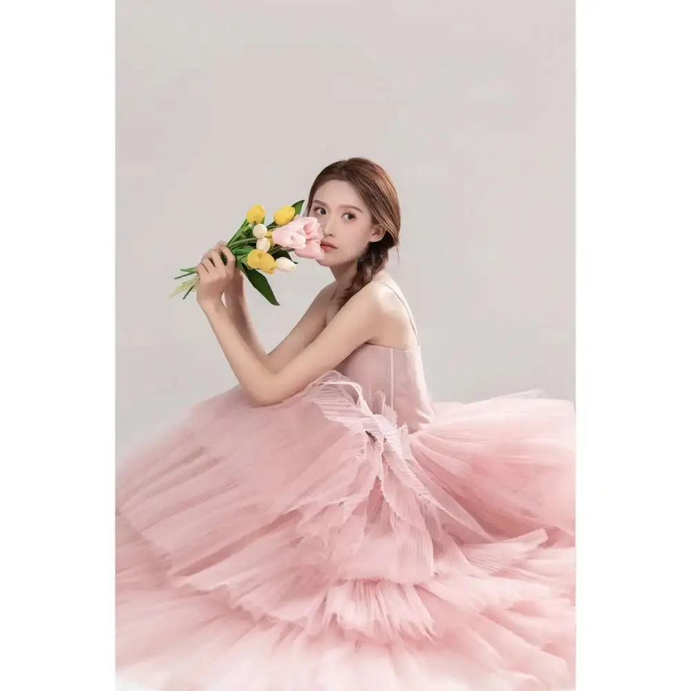 A soft pink tulle wedding photography dress with a fitted bodice and voluminous layered skirt for elegant bridal wear