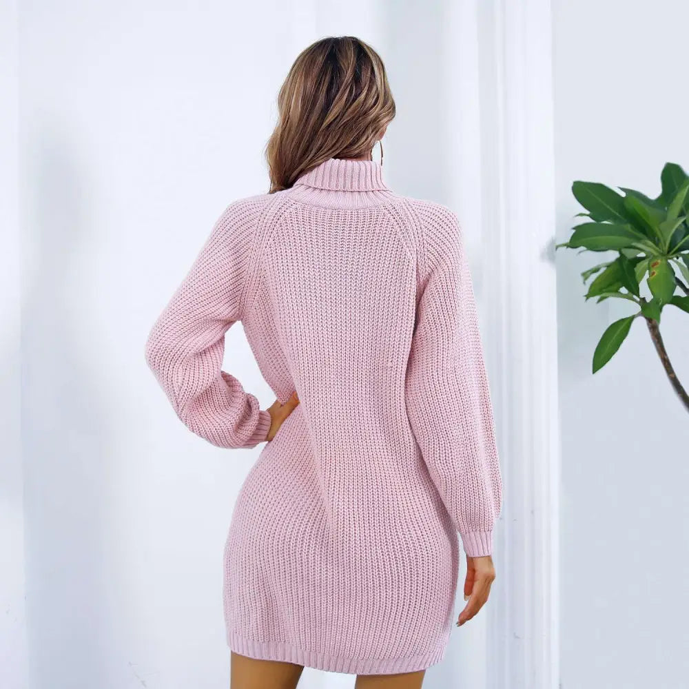 A soft pink winter turtleneck sweater dress with long ribbed knit sleeves and a black belt detail