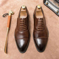 A pair of polished brown leather plus size casual shoes with cap toe oxford design and matching laces