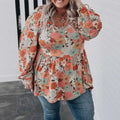 A plus size woman wears a casual loose floral chiffon peplum shirt in orange teal and brown on an off white background