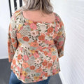 A plus size casual loose floral chiffon peplum shirt in peach coral and mint on off-white worn by a woman