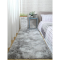 A plush gray shaggy carpet floor mat with soft fluffy texture lies on the floor in front of a bed