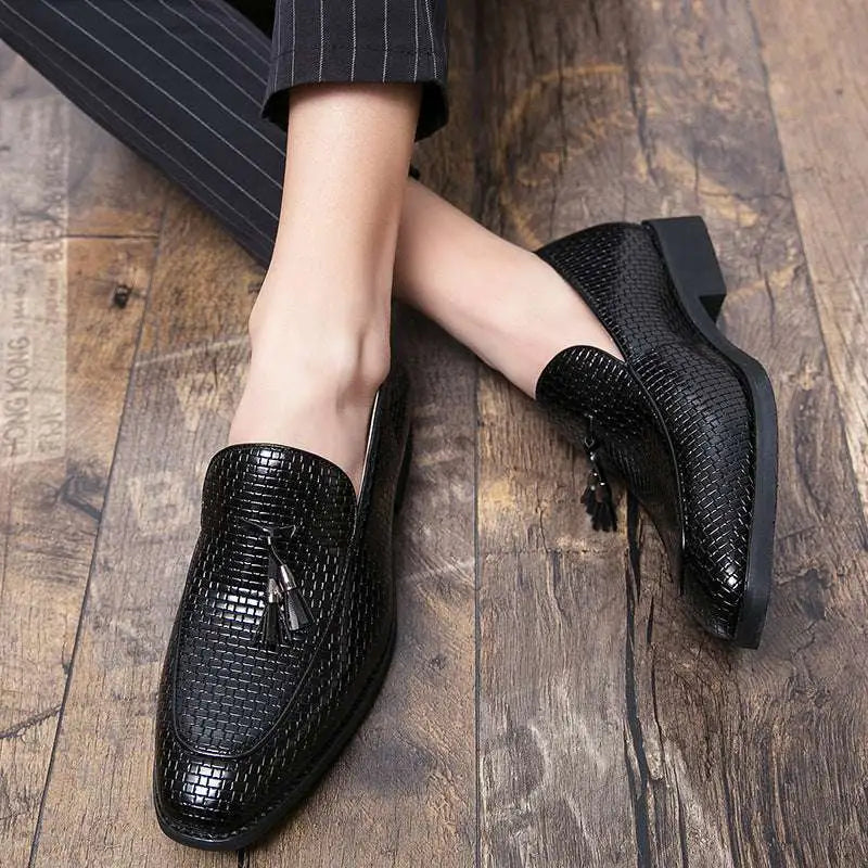 Black pointed men’s slip woven leather shoes featuring glossy finish and tassel detailing for formal wear