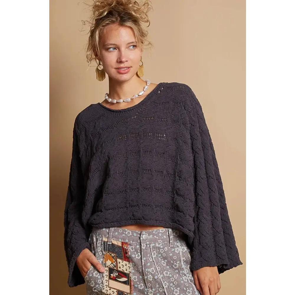 Dark gray cable knit cropped sweater with relaxed fit and textured bell sleeves in knit cropped sweater style