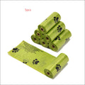 Green plastic dog poop bags with black paw prints in a portable poop bag dispenser for easy waste cleanup