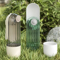 Two translucent ribbed pet water cups in muted gray-green and emerald green with white caps for green dog walking