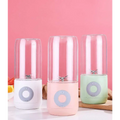 Three portable usb automatic mini juicer cups with clear glass jars and pastel silicone bases in white pink and mint green