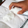 White foam grease cleaning spray dispensing bubbly foam onto quilted fabric of pink puffer jacket with fur-lined hood