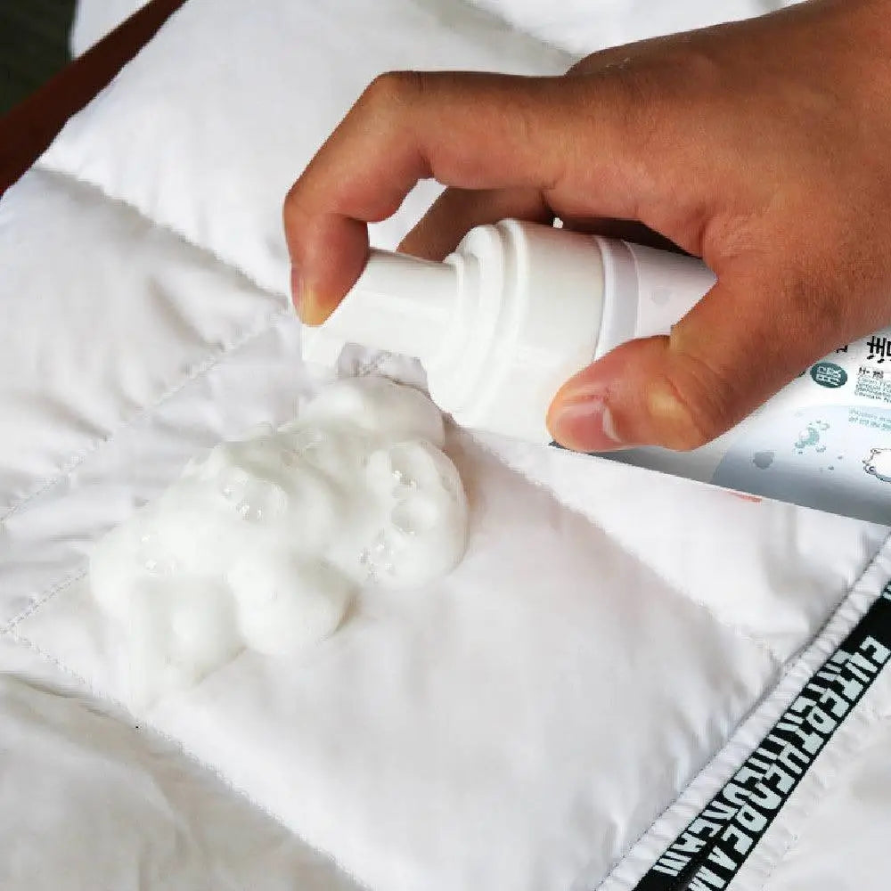 White foam grease cleaning spray dispensing bubbly foam onto quilted fabric of pink puffer jacket with fur-lined hood
