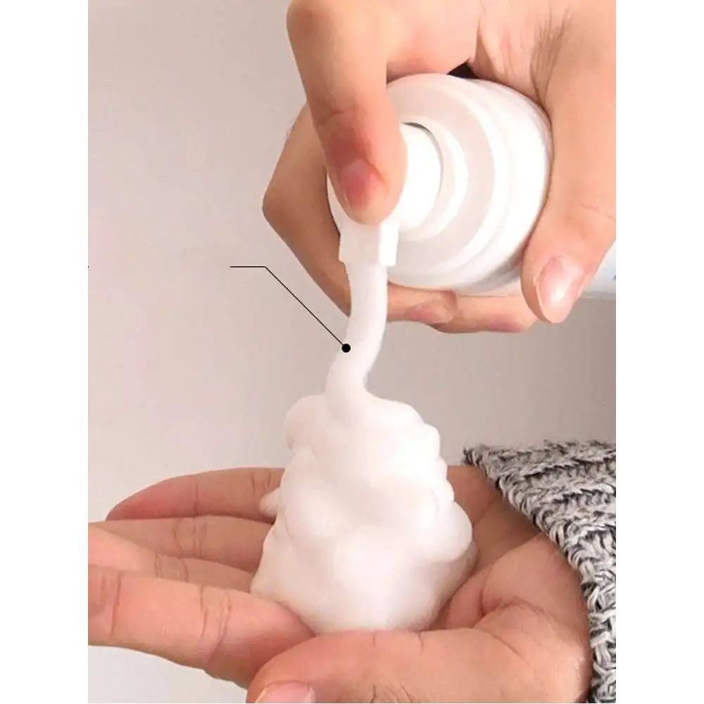 White plastic pump bottle dispensing thick foamy grease cleaning spray into open palm for pink puffer jacket care
