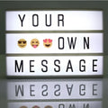 A premium led cinema lightbox with glowing white panels and black letter tiles spelling your own message with emojis