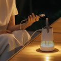 White cylindrical projection mosquito repellent night light lantern with transparent glass base and top handle emitting warm light