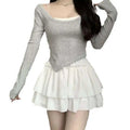 Gray long-sleeved top with square neckline and asymmetrical hem layered over white camisole with pure desire style slimming ballet skirt