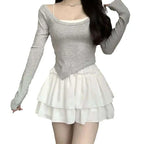 Gray long-sleeved top with square neckline and asymmetrical hem layered over white camisole with pure desire style slimming ballet skirt