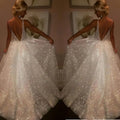 Pure white sequined wedding evening dress with a deep v-back and a flowing skirt shown from the back side