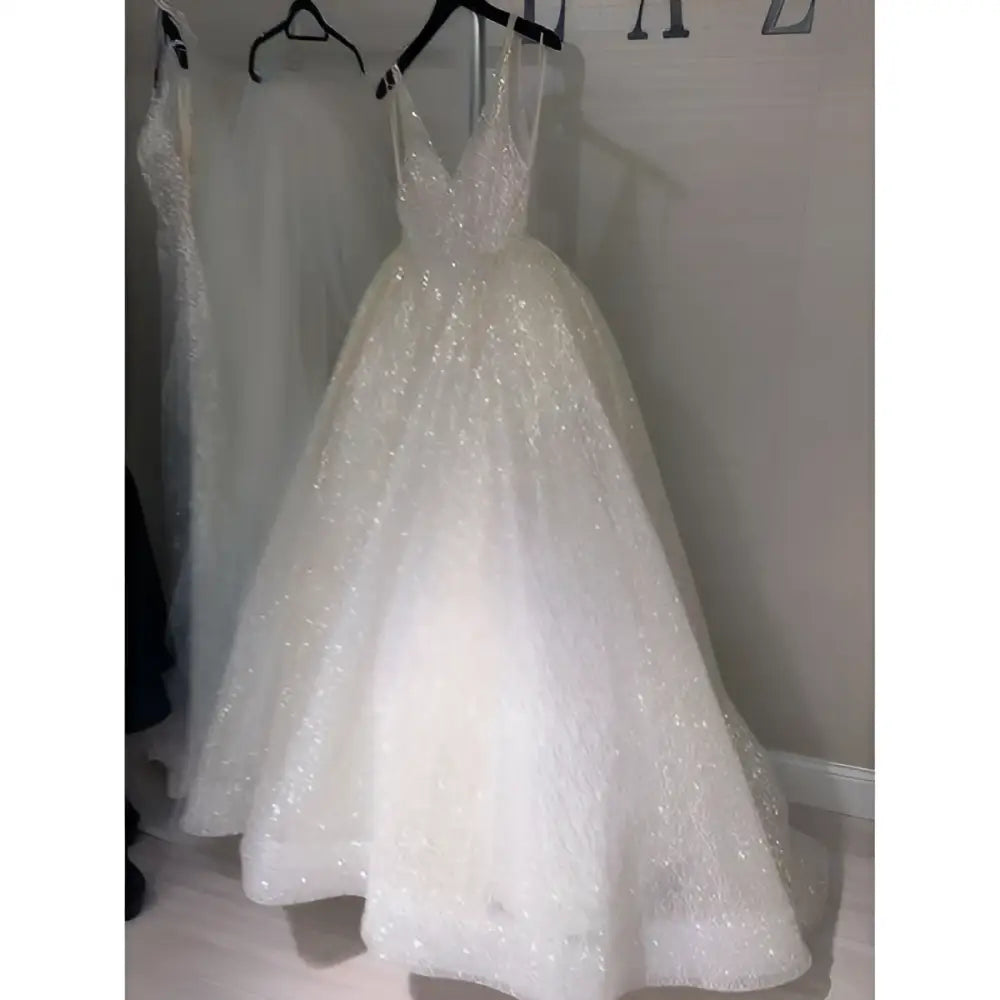 A pure white sequined wedding evening dress with a deep v-neckline and delicate spaghetti straps