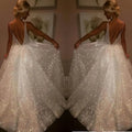 Pure white sequined wedding evening dress with a deep v-back and flowing skirt shown from the back side