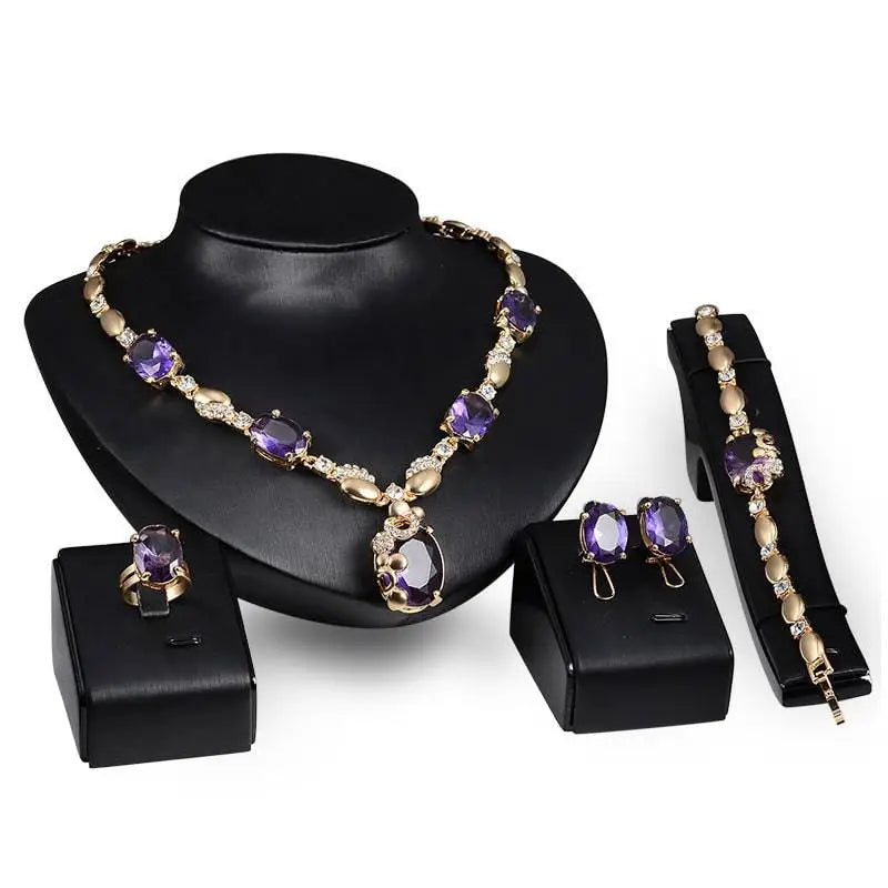 Elegant gold-toned purple amethyst united states fashion jewelry set with oval-cut stones and clear crystals on black busts