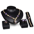 Elegant gold-toned purple amethyst united states fashion jewelry set with oval-cut stones and clear crystals on black busts