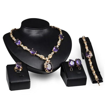 Elegant gold-toned purple amethyst united states fashion jewelry set with oval-cut stones and clear crystals on black busts