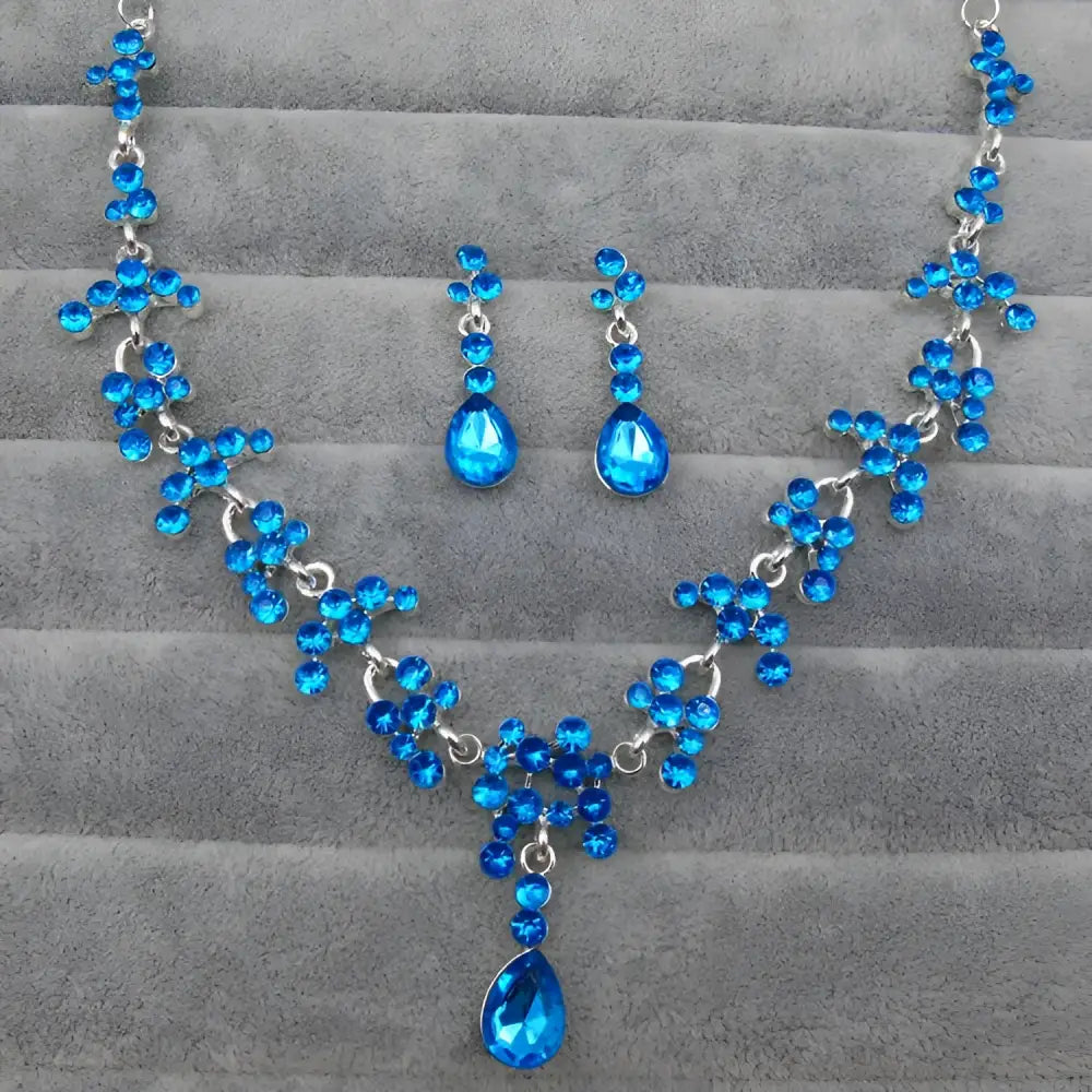 A sparkling blue crystal wedding jewelry necklace and earring set with silver chain and intricate floral designs