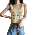 A cream-colored knitted sleeveless embroidered floral camisole with blue floral embroidery and diamond cable knit design