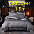 Dark gray satin bed cover with subtle sheen and embroidered logo at the foot in a purple satin embroidered four-piece set