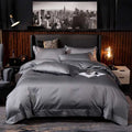 Dark gray satin embroidered four-piece bed sheet set with subtle embroidered logo on fabric main component at duvet foot