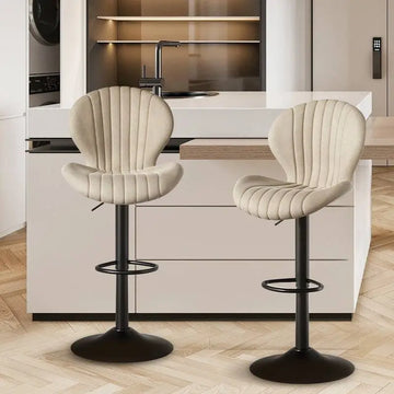 Quilted cream velvet upholstered bar stools with black metal bases and footrests for luxury women’s fashion seating