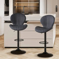 Two sleek dark gray upholstered bar stools with vertical stitching and black metal bases for luxury womens fashion